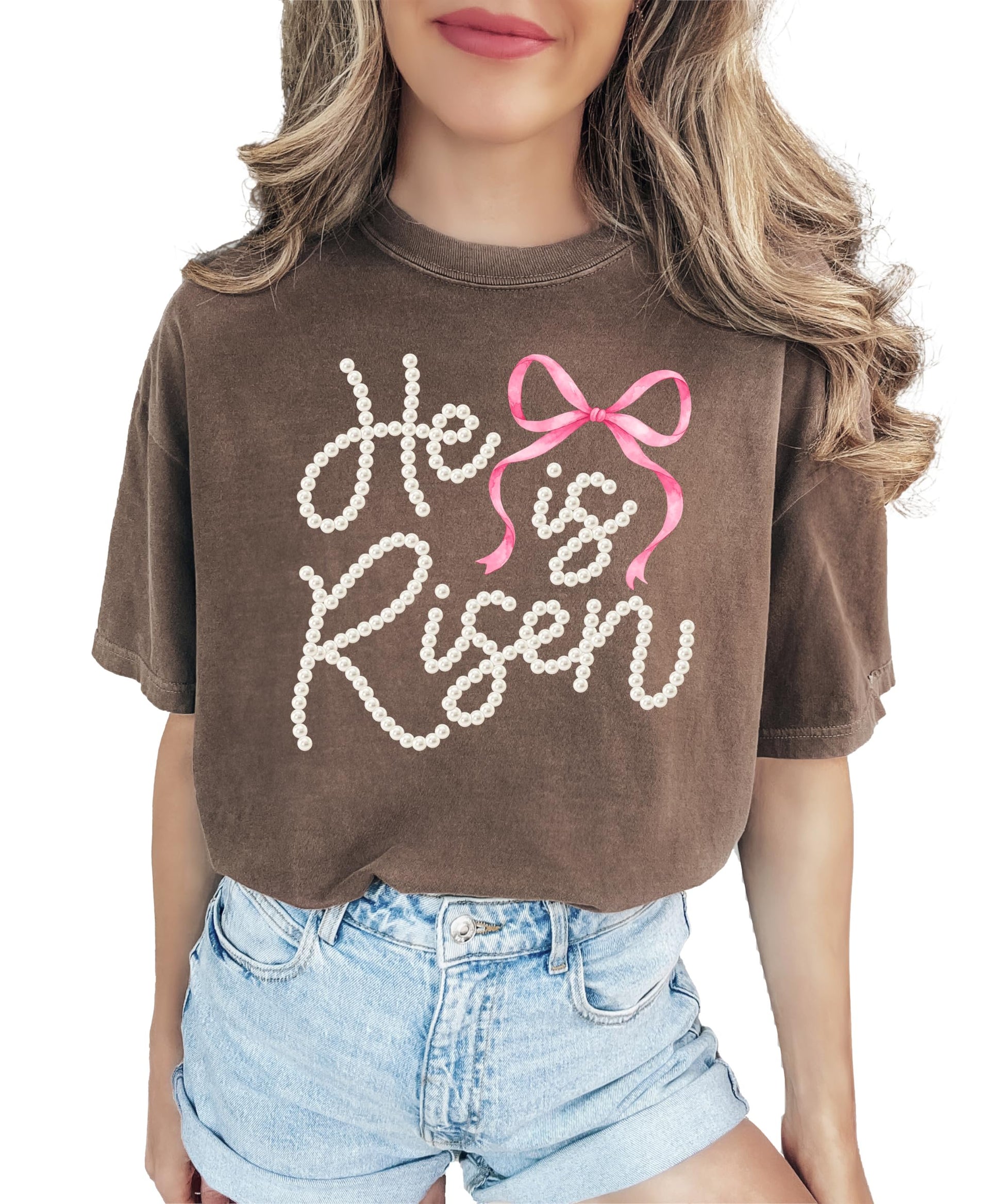 Close-up of He Is Risen pearl lettering and pink bow graphic print on women's Easter tee