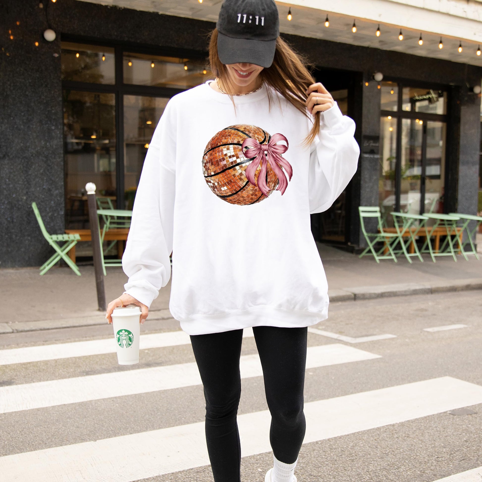 Detail shot of coquette bow and disco basketball print on a cozy gray women's sweatshirt