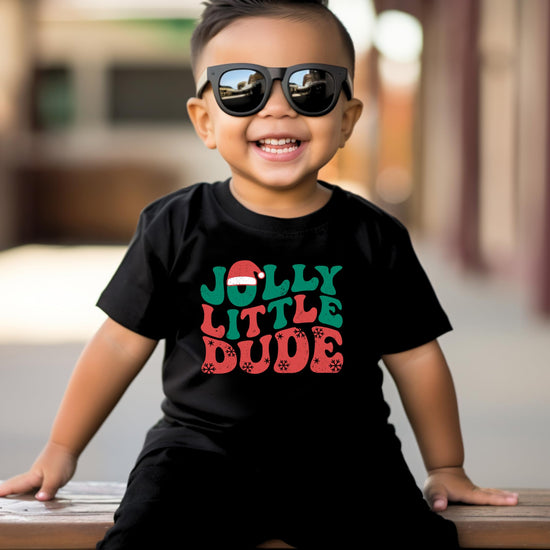 Kids black Christmas shirt with Jolly Little Dude graphic laid flat on styled surface