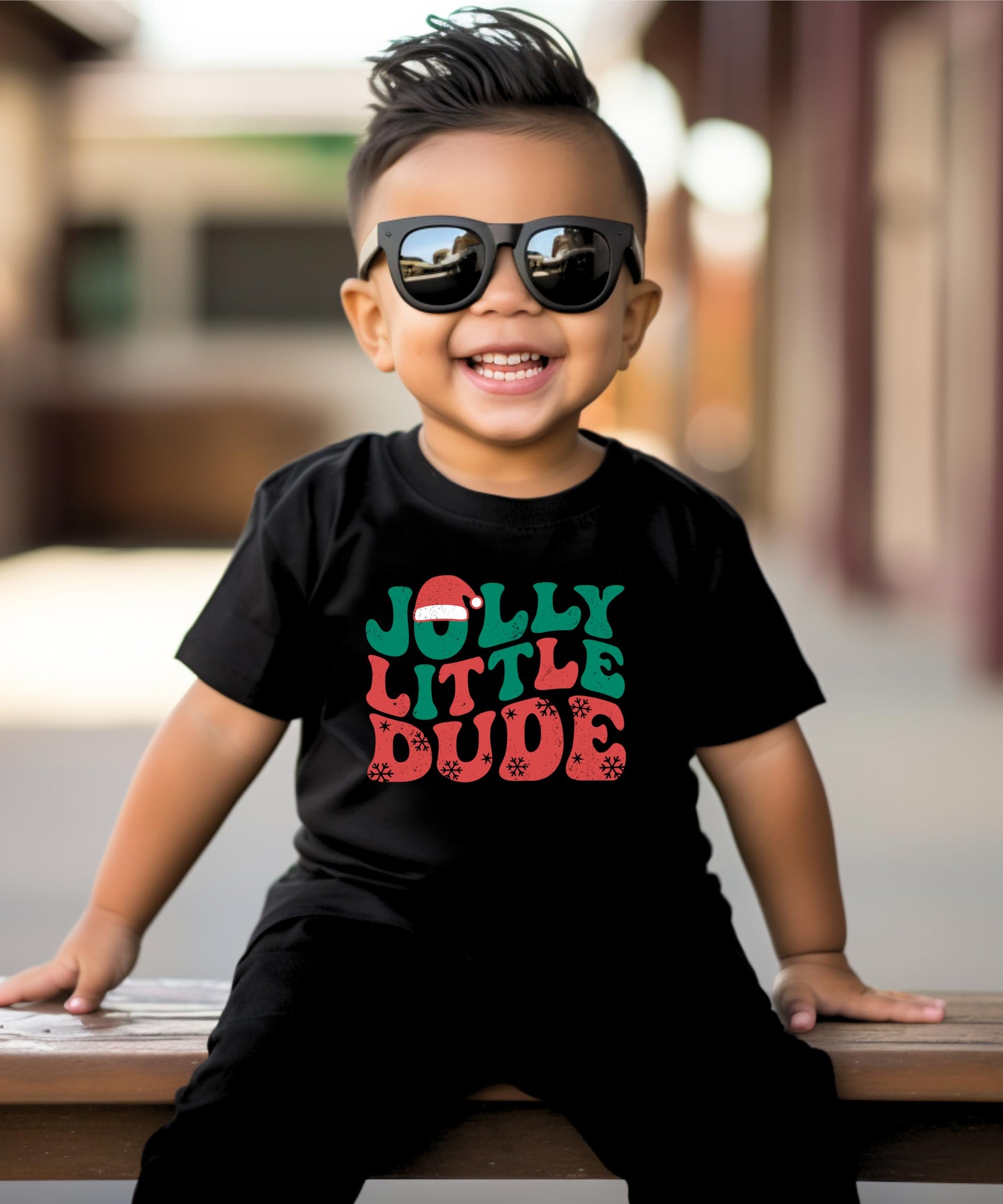 Kids black Christmas shirt with Jolly Little Dude graphic laid flat on styled surface