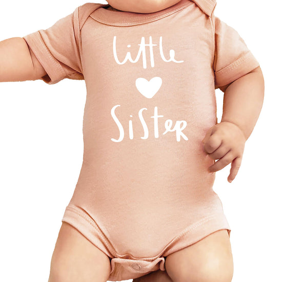 White Little Sister heart graphic bodysuit on mauve background for baby girls by Olive Loves Apple