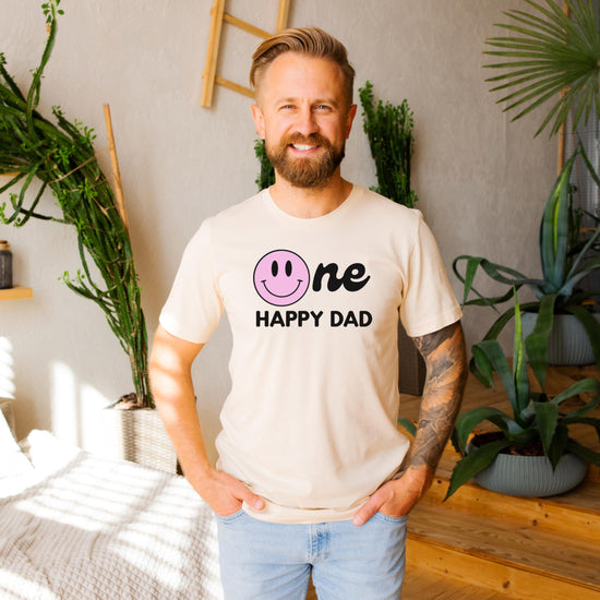 Flat lay of full One Happy Family matching family birthday shirt set in natural tone