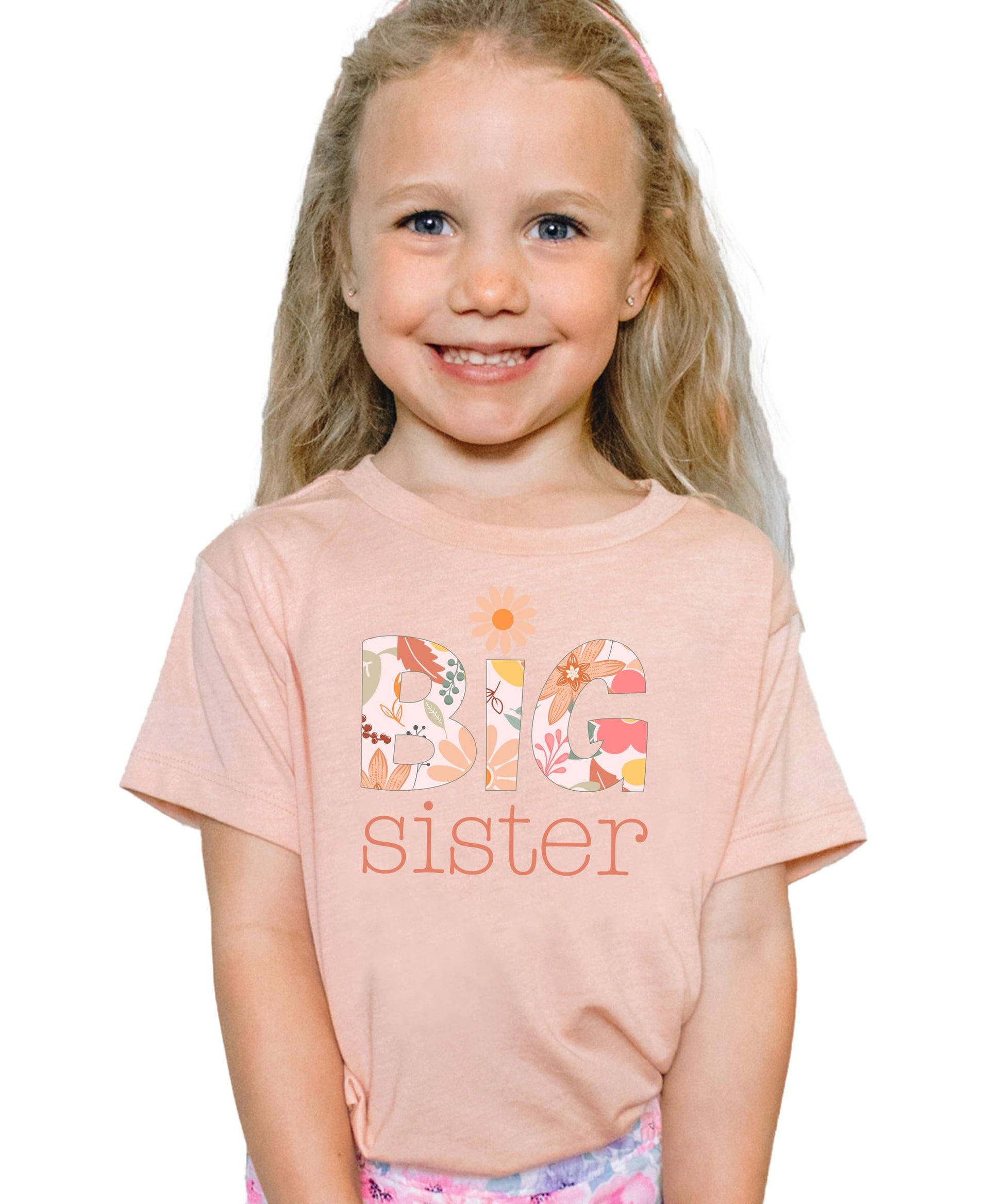 Close-up of floral daisy Big Sister design printed on a soft peach youth tee