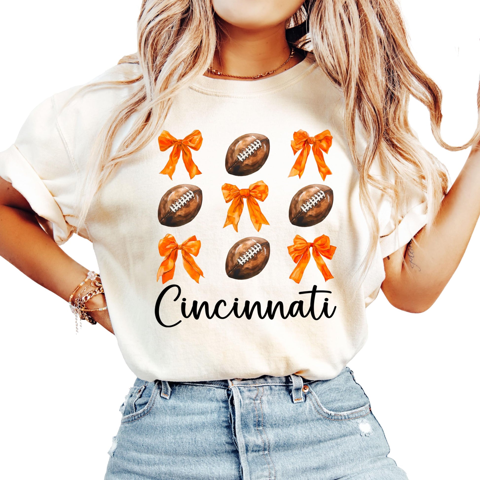 Ivory women's Cincinnati football t-shirt with girly orange bows and footballs graphic design