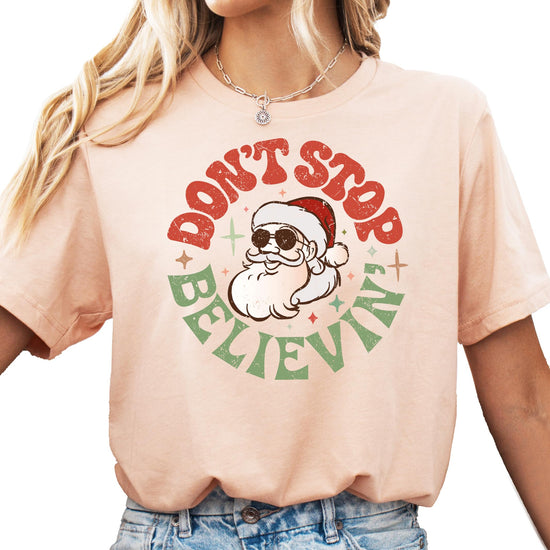 Women's natural color Christmas tee with Don't Stop Believing Santa graphic print