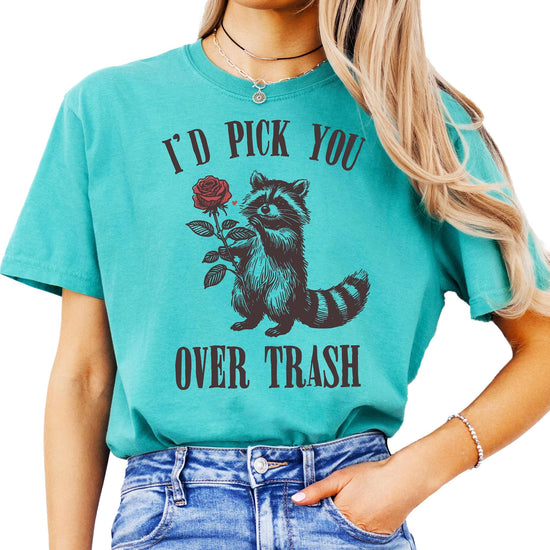 Close-up of 'I'd Pick You Over Trash' raccoon graphic print on soft ivory women's t-shirt