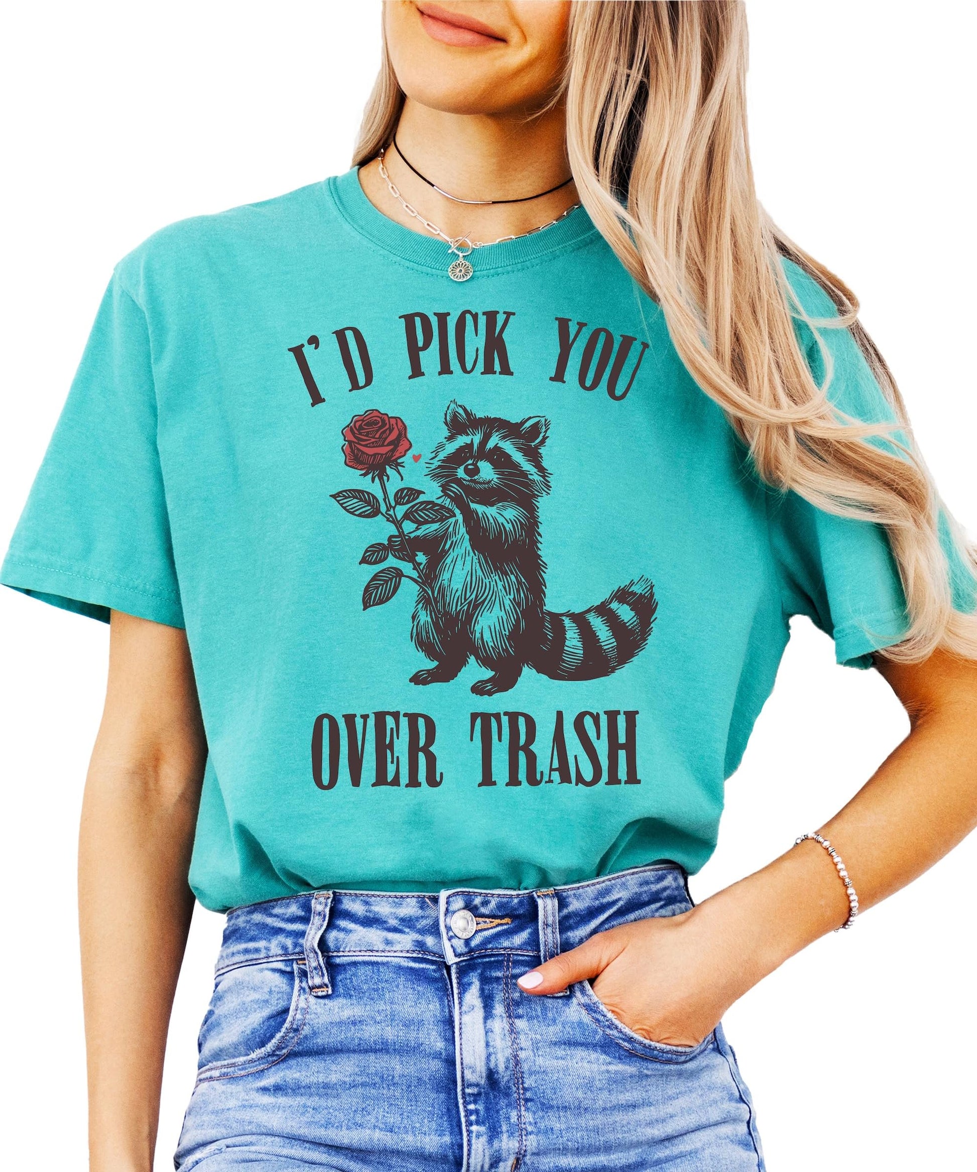 Close-up of 'I'd Pick You Over Trash' raccoon graphic print on soft ivory women's t-shirt