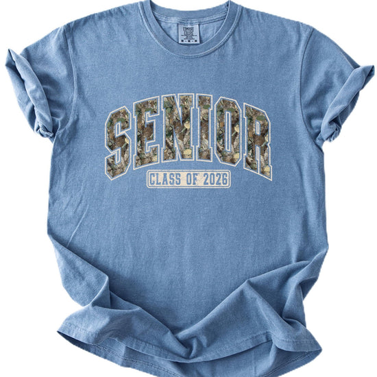 Unisex camo varsity graphic tee with bold SENIOR lettering and Class of 2026 badge on pepper shirt