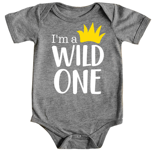 Baby boy wearing a white Wild One first birthday bodysuit with a yellow crown graphic