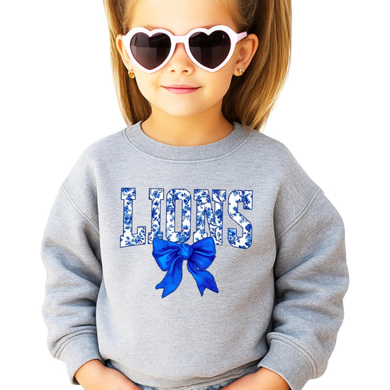 Close-up of bold blue floral LIONS print and decorative bow on black sweatshirt