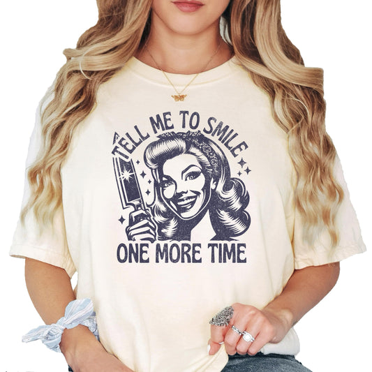 Ivory women's graphic tee with retro housewife illustration and text 'Tell Me to Smile One More Time'