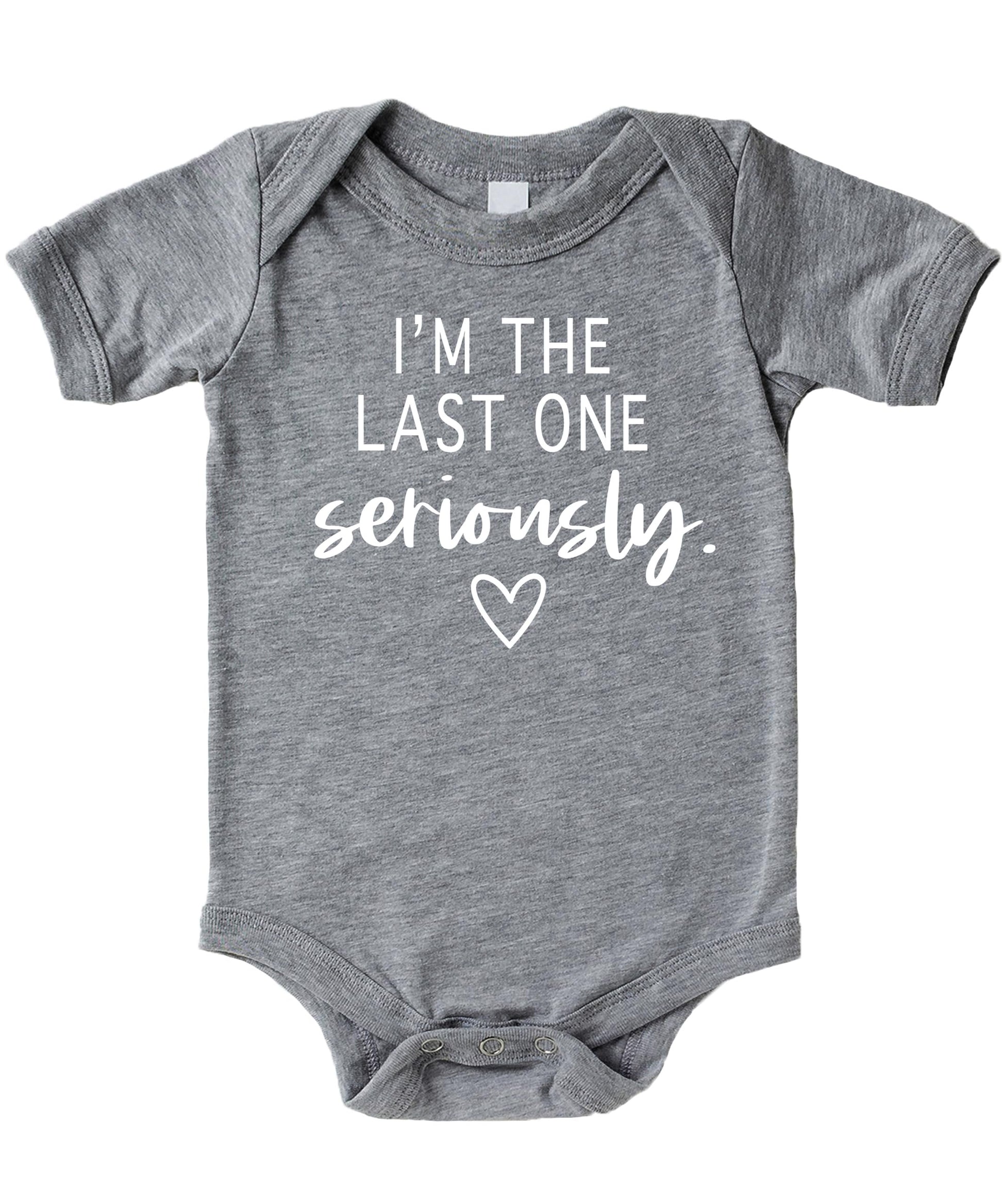 White graphic baby bodysuit on mauve background reading I'm The Last One Seriously — funny pregnancy reveal newborn outfit