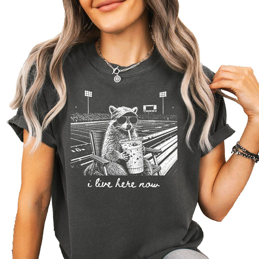 Lifestyle shot of I Live Here Now football mom graphic tee styled for tailgate or spirit night