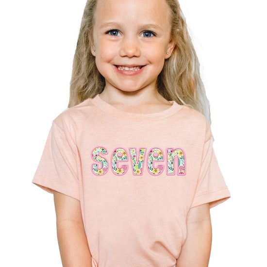 Peach girls birthday shirt with floral embroidered seven design and pink accents