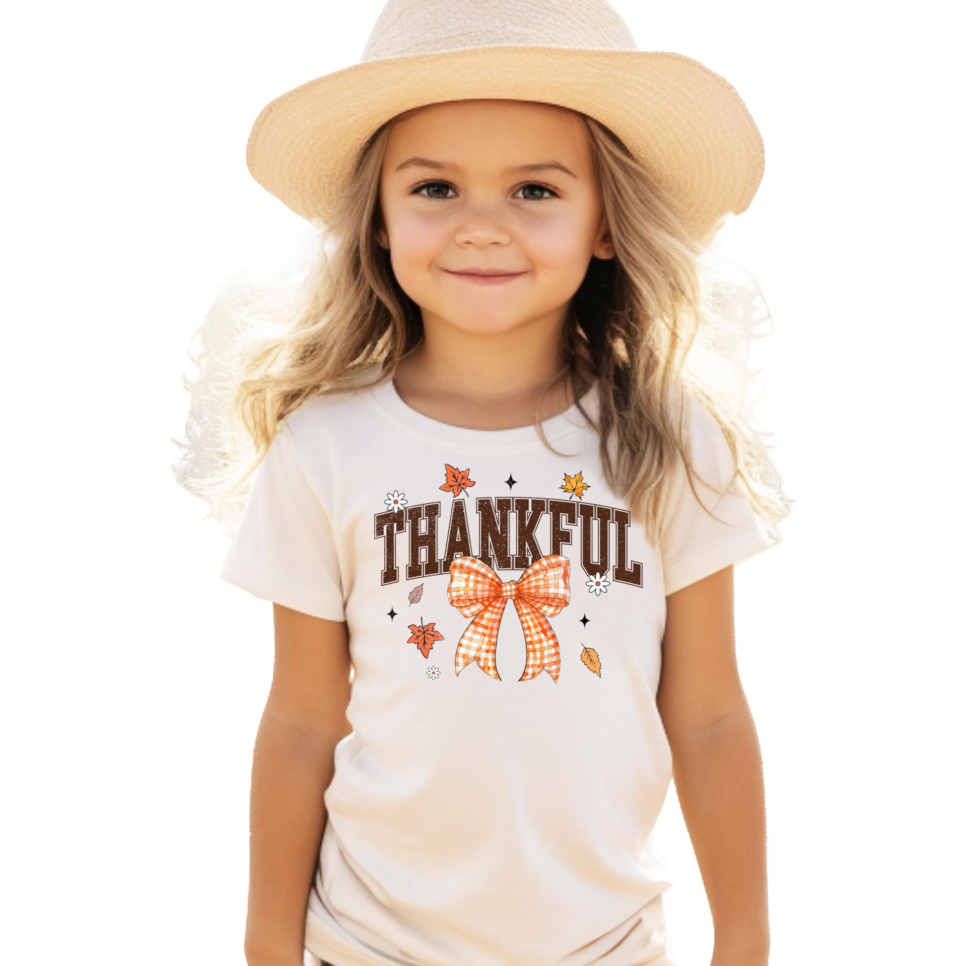 Close-up of orange Thankful text with decorative gingham bow graphic on kids tee
