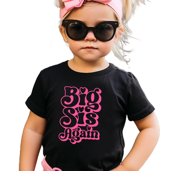 Close-up of Big Sis Again groovy pink heart graphic on natural kids shirt