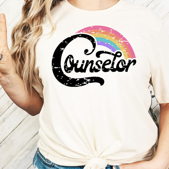 Flat lay of black women's counselor shirt with rainbow graphic design