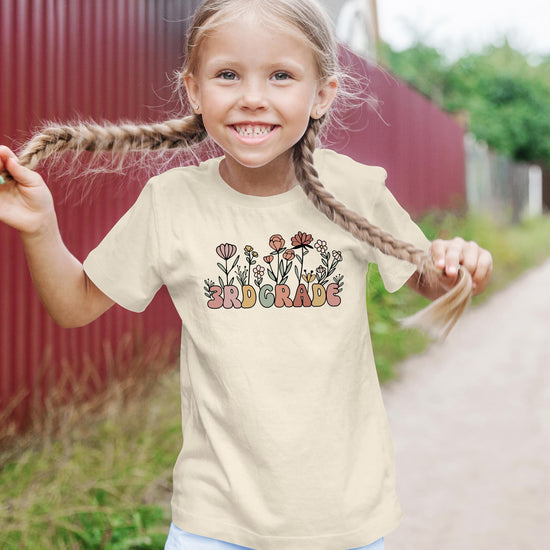 3rd grade girls graphic tee with whimsical flower design, detail shot on military green shirt