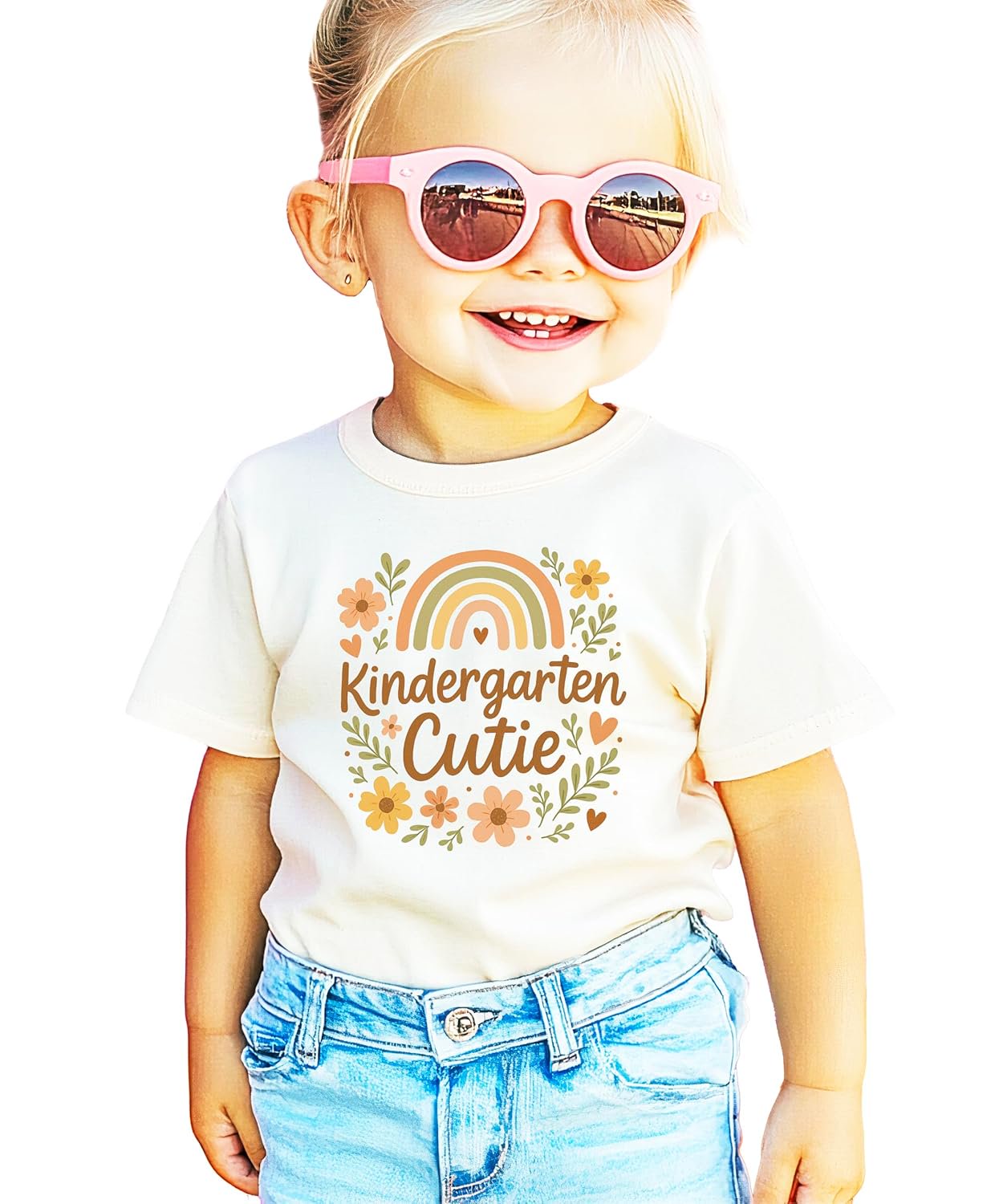 Close-up of hand-lettered Kindergarten Cutie script with wildflower and rainbow design on natural shirt