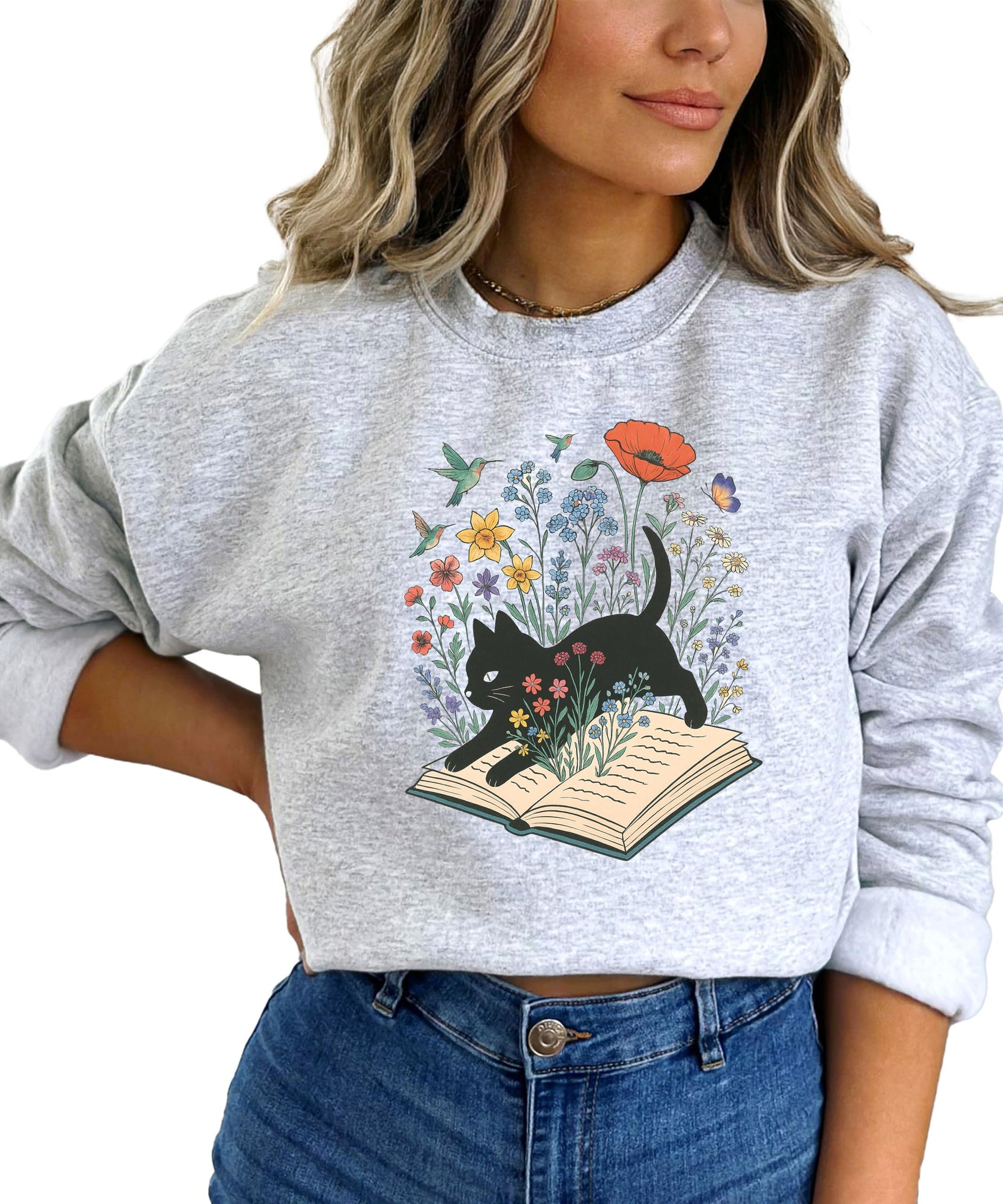 Flat lay of white book lover sweatshirt with black cat nestled in flowers and butterflies graphic print