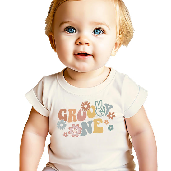 Baby girl wearing Groovy One first birthday shirt with retro daisy design