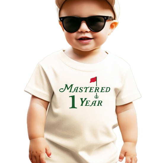 Natural colored toddler tee with golf-themed Mastered 1 Year first birthday graphic for boys