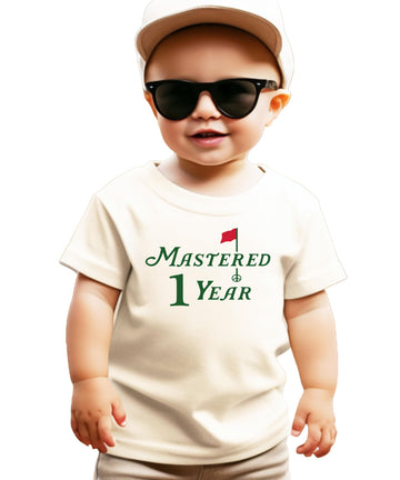 Natural colored toddler tee with golf-themed Mastered 1 Year first birthday graphic for boys