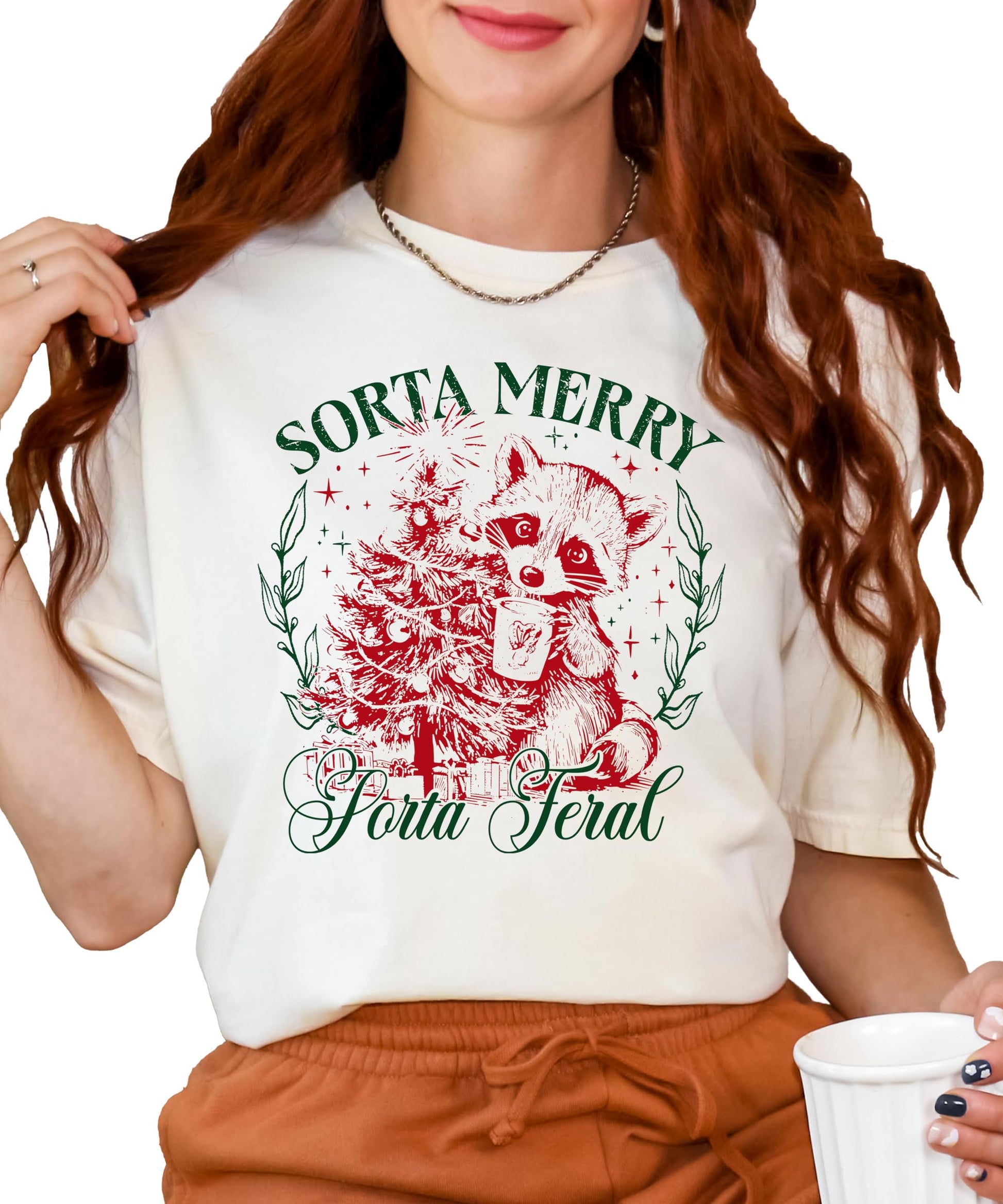 Close-up of Sorta Merry Sorta Feral raccoon holiday print on ivory women's graphic tee