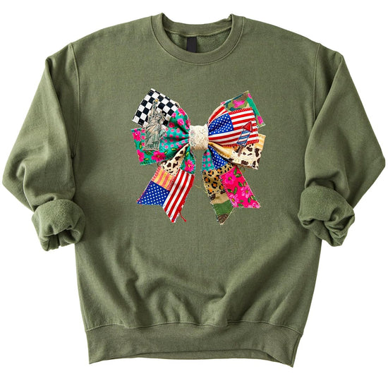 White crewneck sweatshirt with ink-printed patriotic ribbon bow featuring stars, stripes, florals, and Americana patchwork design