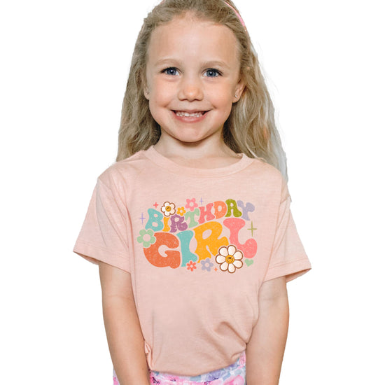 Close-up of groovy flower birthday girl graphic print on natural kids tee