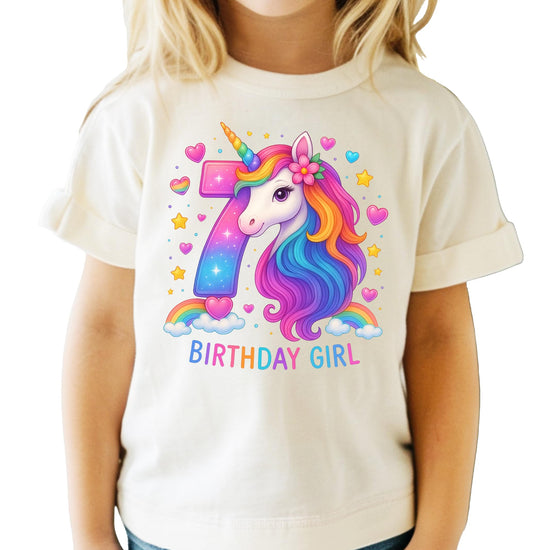 Flat lay of pink girls unicorn birthday tee showing rainbow horse graphic and number 7