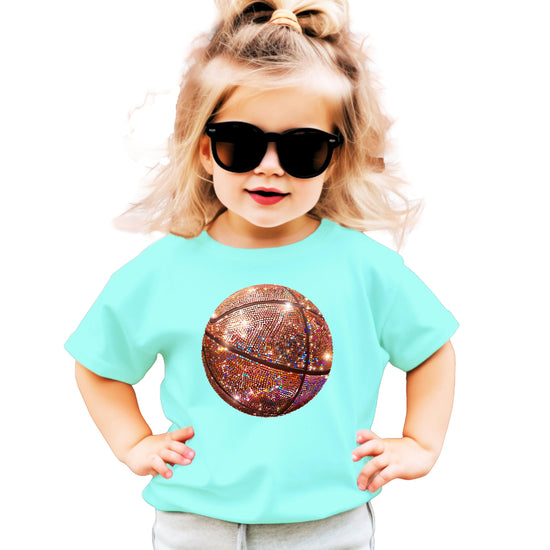 Close-up of faux glitter basketball design on a pink girls graphic t-shirt
