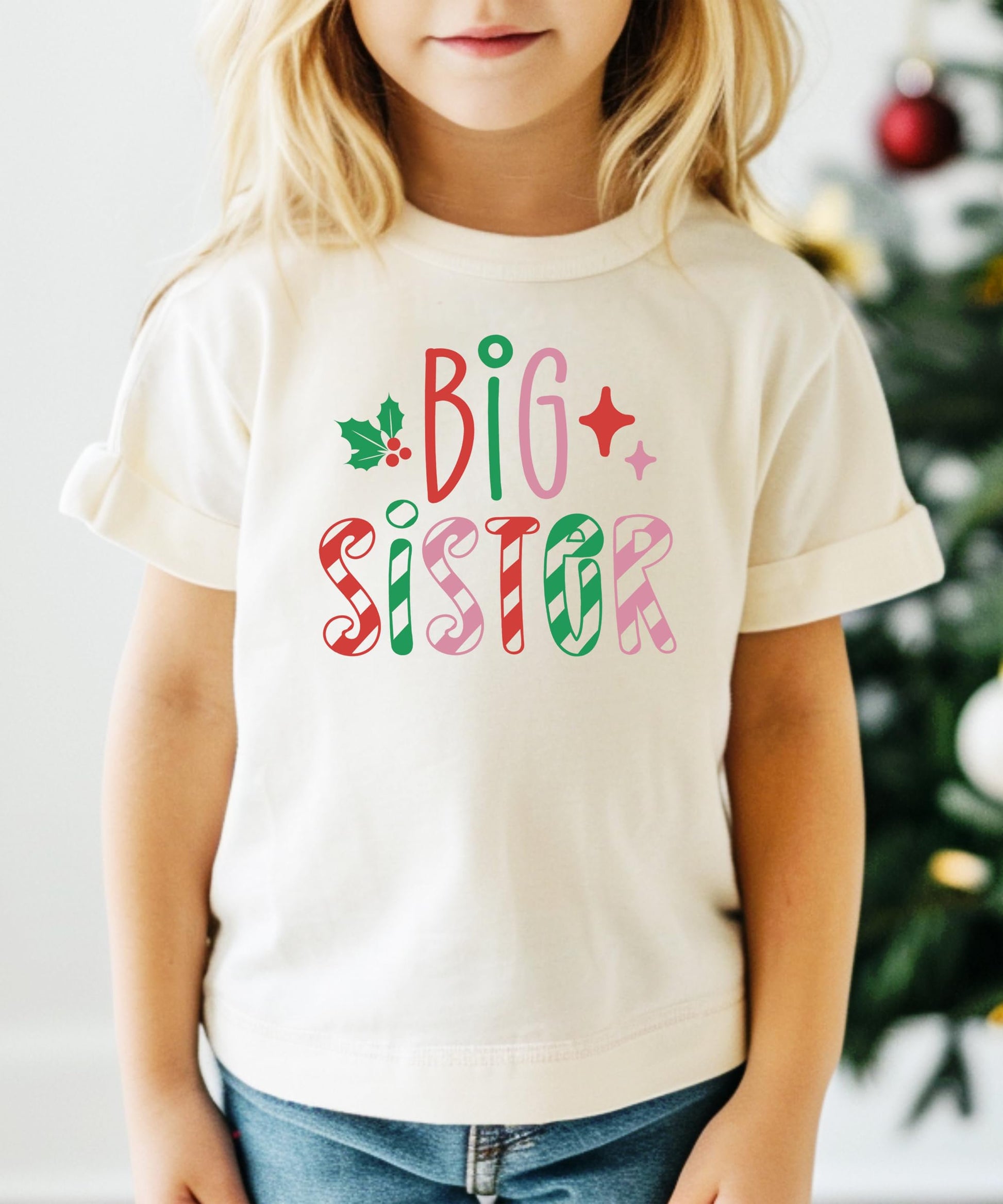 Front view of festive big sister Christmas shirt with colorful candy cane stripes for girls