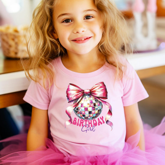 Detail shot of vibrant pink bow and disco ball graphic on kids birthday girl graphic tee