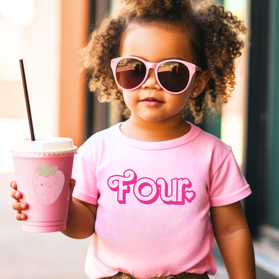 Flat lay of pink age four birthday shirt with cute girly heart print
