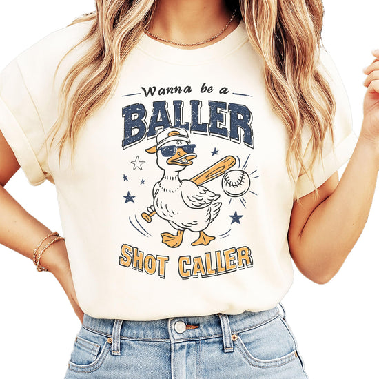 Model wearing ivory baseball themed graphic tee with funny duck baller design