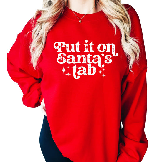 Close-up of 'Put It on Santa's Tab' graphic print detail on red women's Christmas sweatshirt