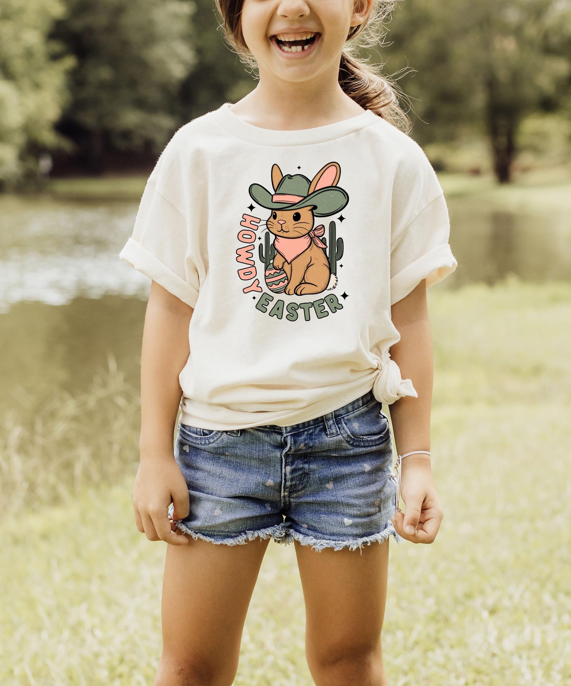 Flat lay of peach youth Howdy Easter western shirt with cowboy bunny, cactus, and Easter egg artwork