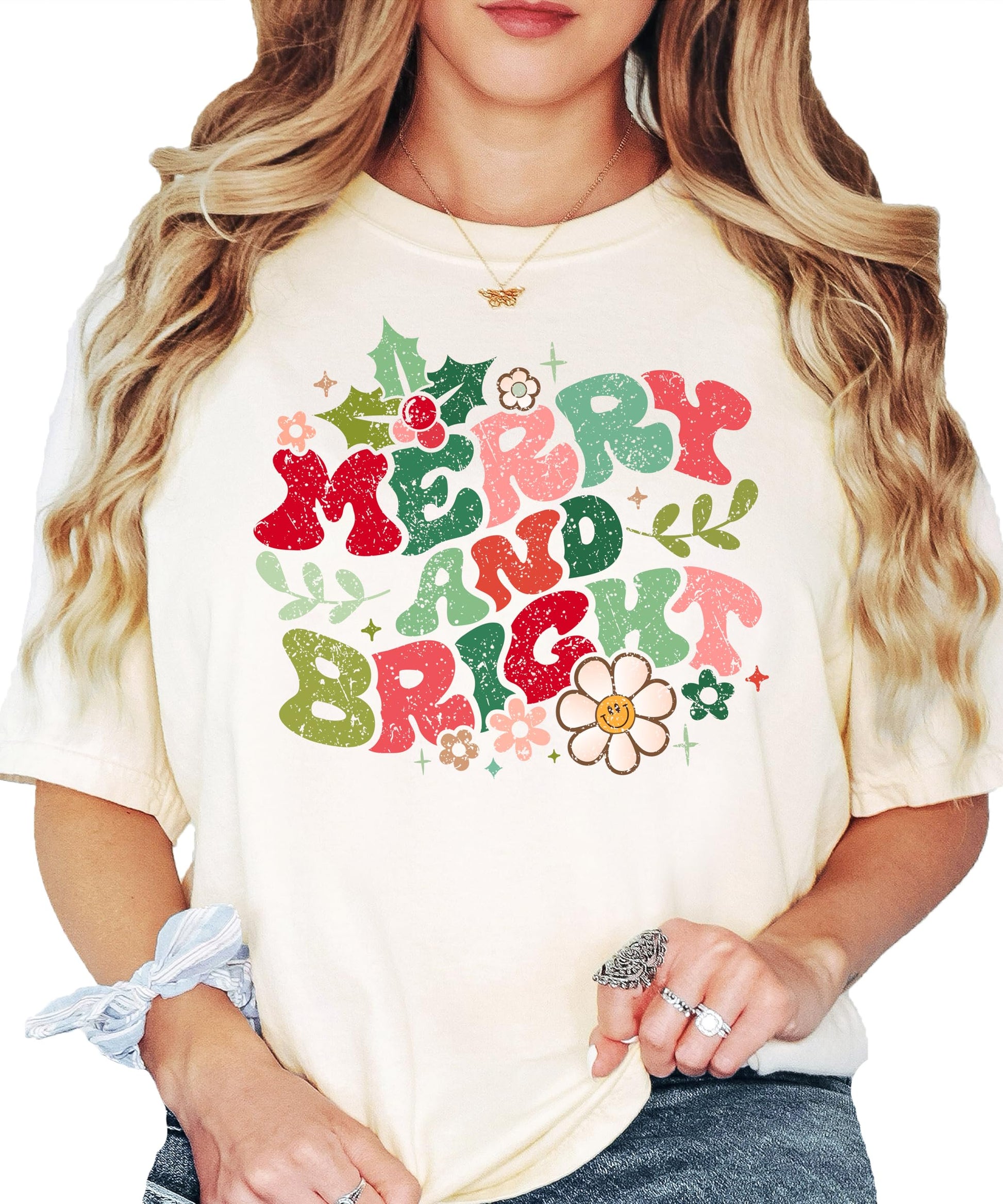 Close-up of distressed Merry and Bright Christmas graphic print with floral details on ivory tee