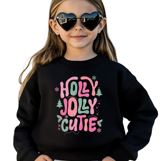 Kids black crewneck sweatshirt with pink and green Holly Jolly Cutie bubble letter Christmas graphic