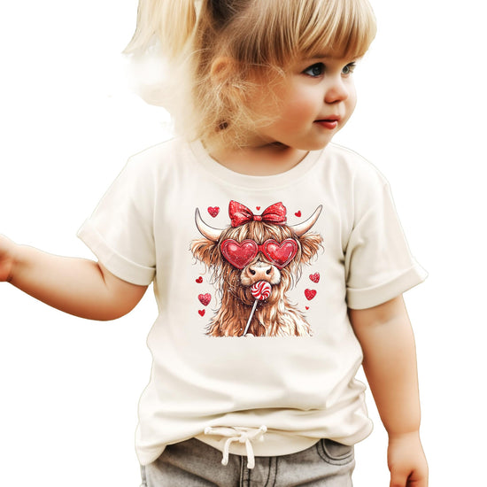 Flat lay of kids' pink Valentine's Day Highland cow shirt with hearts print