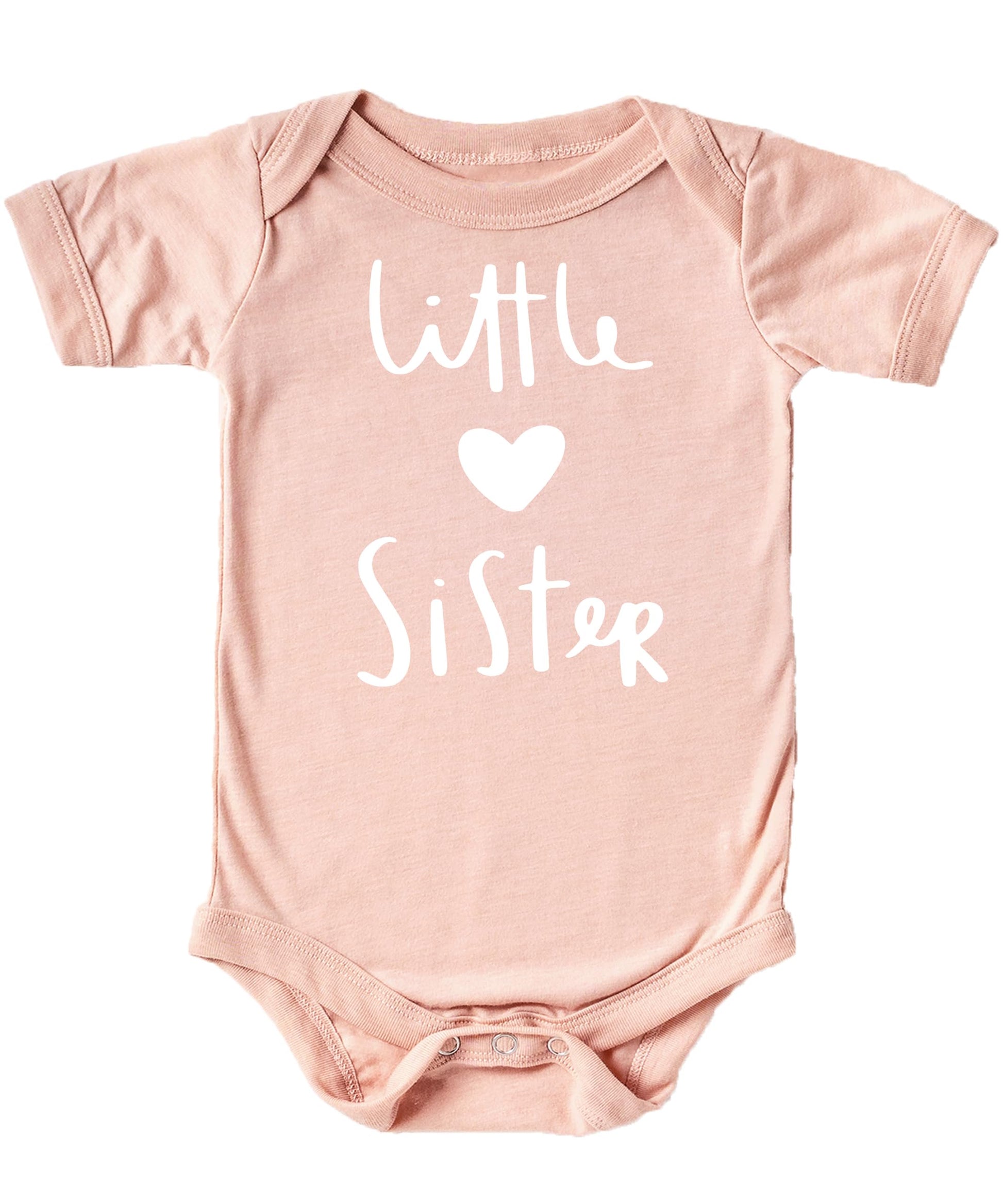 Flat lay of white Little Sister graphic bodysuit with heart detail on mauve surface