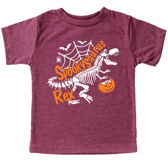 Close-up of skeleton dinosaur graphic on kids Halloween tee — bold white print on burgundy