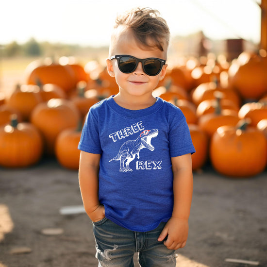 Flat lay of military green toddler shirt with Three Rex birthday design