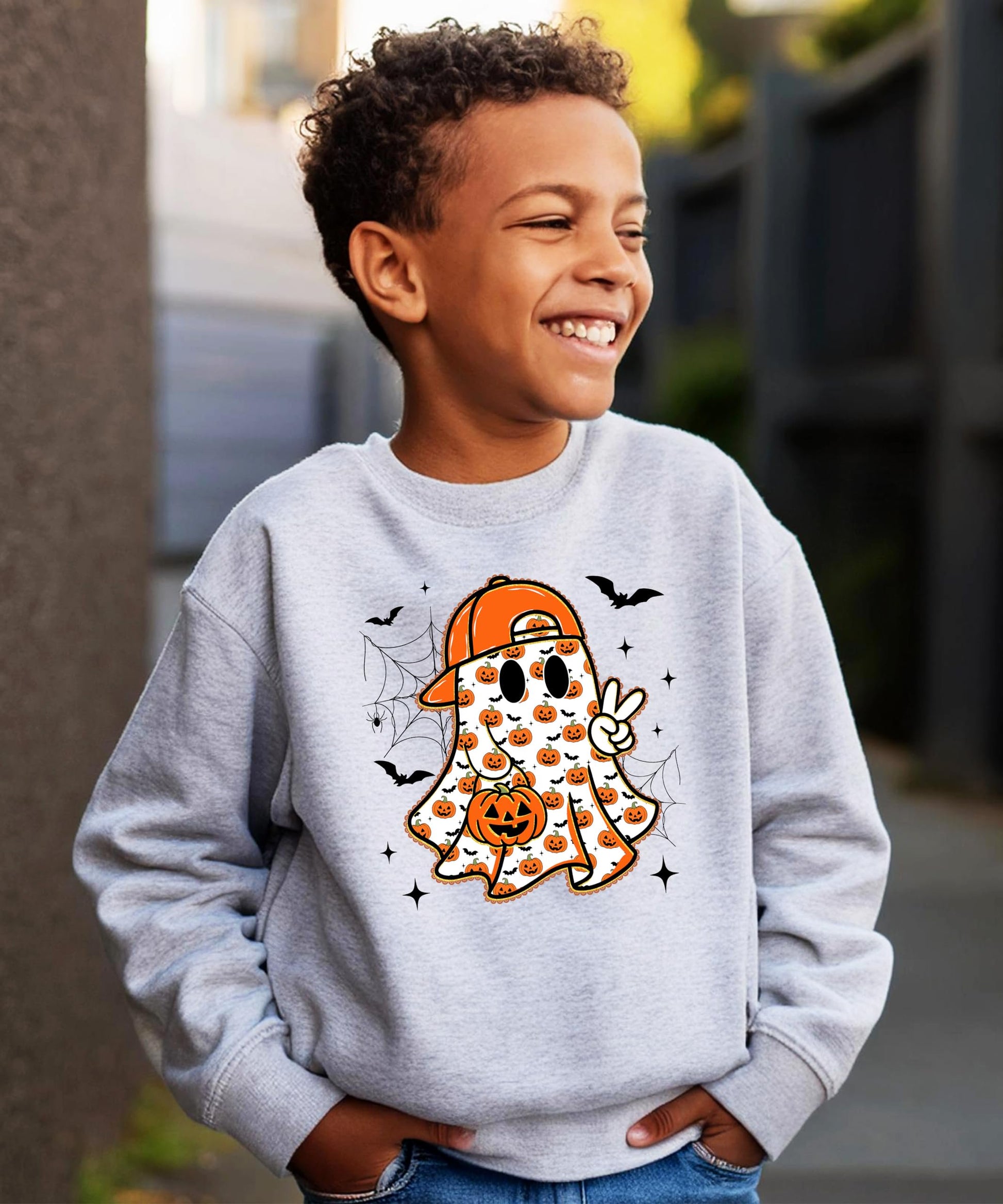 Youth Halloween graphic sweatshirt laid flat showing full ghost and bat pumpkin design on white pullover