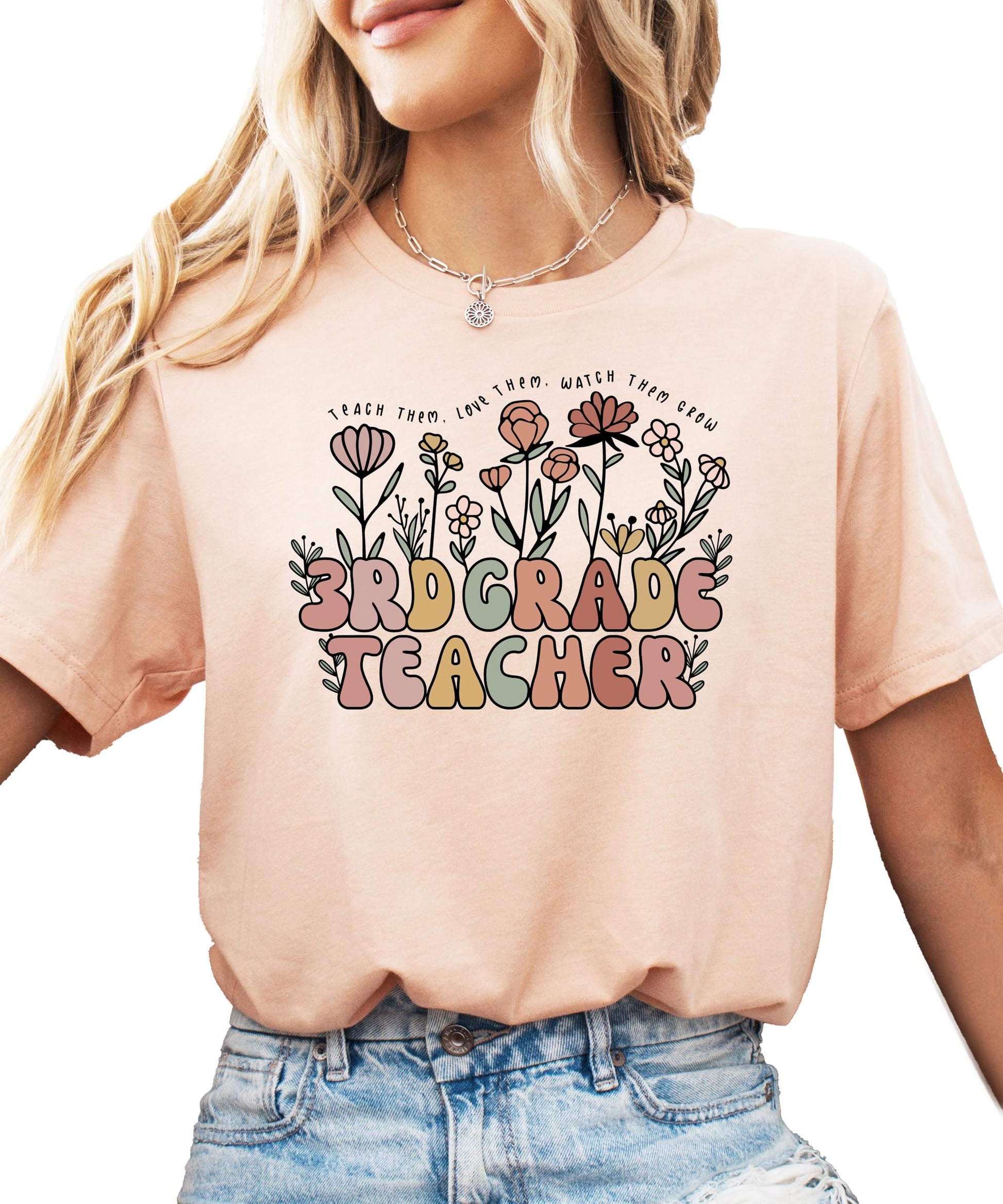 Close-up of floral graphic on women's educator tee with cursive Teach Them Love Them Watch Them Grow text