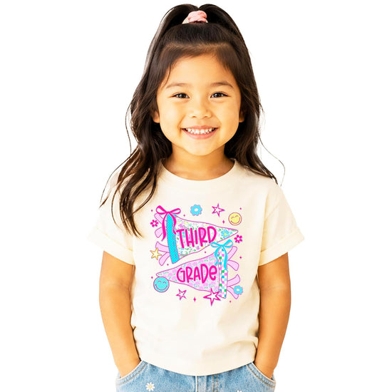 Girls third grade shirt with floral pennant flags spelling out Third Grade in pink lettering on natural cotton tee
