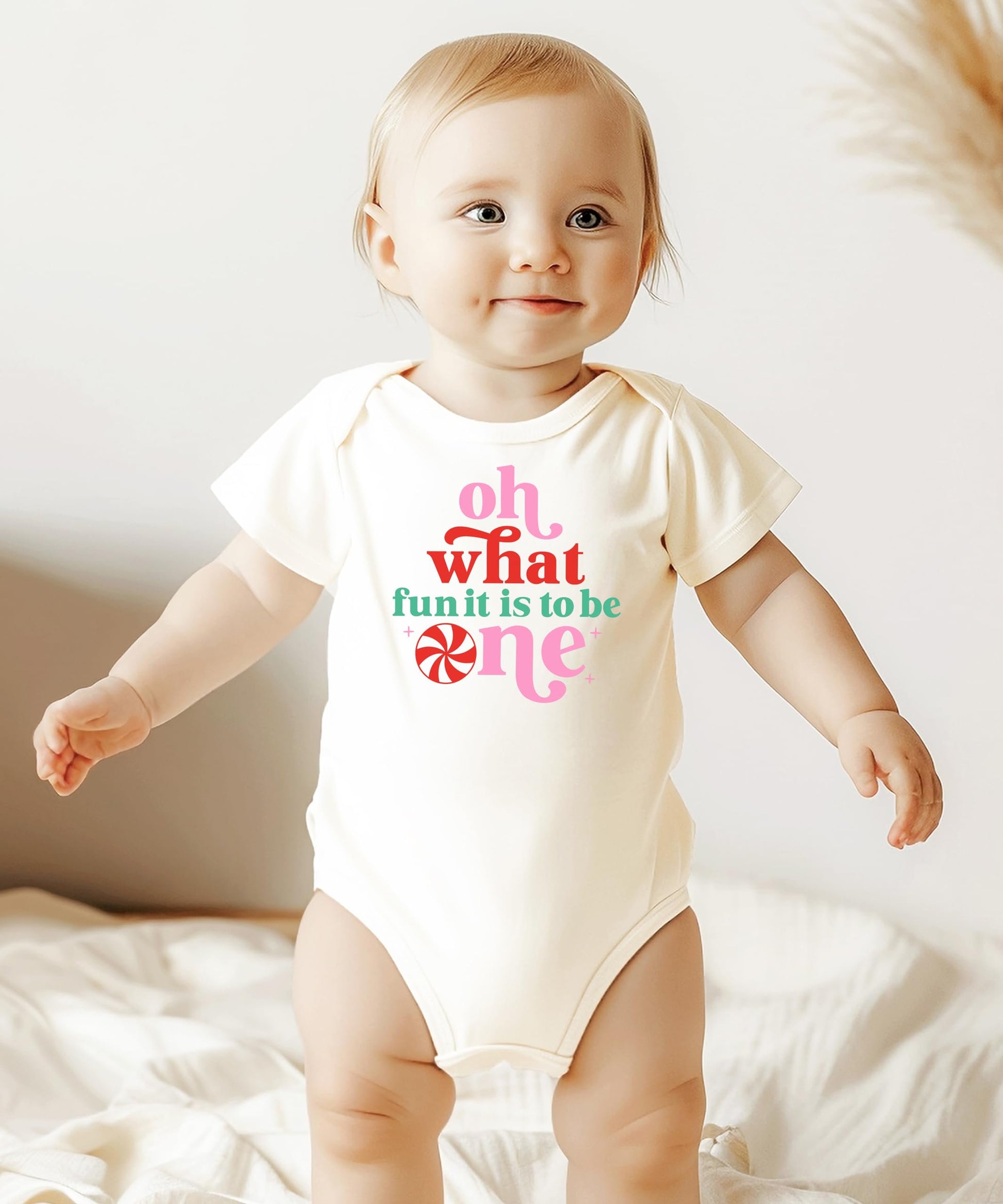 Flat lay of white holiday baby bodysuit with first birthday Christmas design