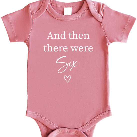 Mauve newborn bodysuit with 'And Then There Were 4' heart sibling announcement design by Olive Loves Apple