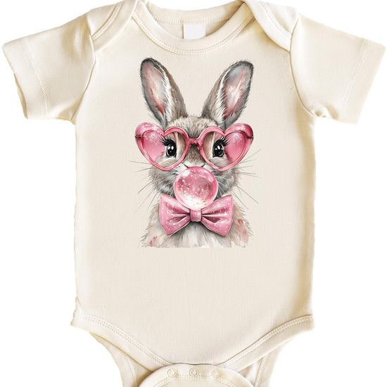 Baby girl bodysuit with Easter bunny blowing bubblegum bubble wearing pink heart-shaped glasses and pink bow on natural fabric